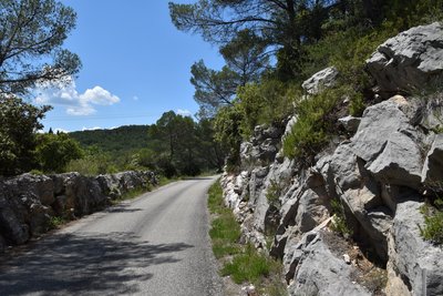 Portion de route entourée de rochers et avec une vue sur les collines verdoyantes environnantes
